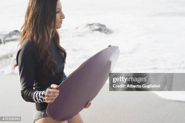 caucasian woman holding skimboard at beach - alberto guglielmi stock pictures, royalty-free photos & images