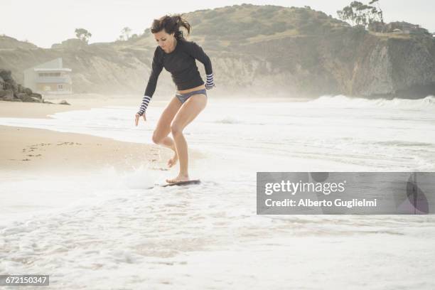 caucasian woman riding skimboard at beach - alberto guglielmi imagens e fotografias de stock