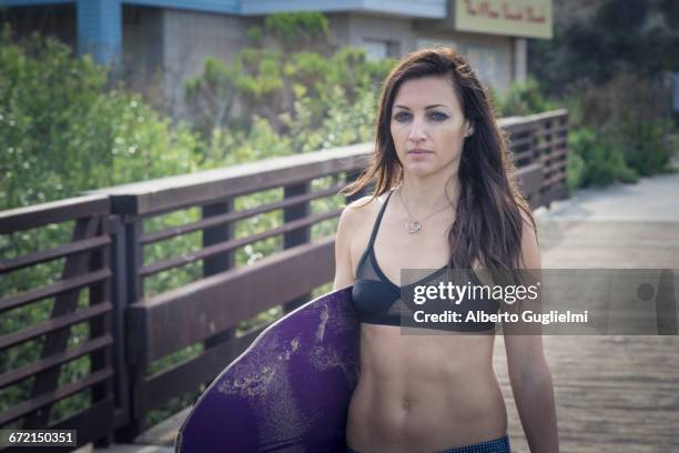 caucasian woman carrying skimboard on boardwalk - alberto guglielmi stock pictures, royalty-free photos & images