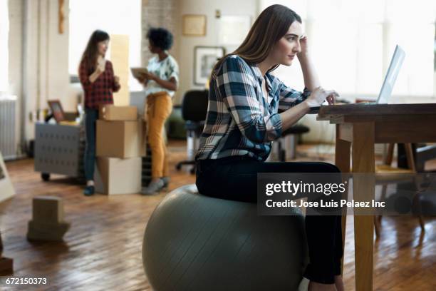 businesswoman sitting on fitness ball using laptop - fitness ball stock pictures, royalty-free photos & images