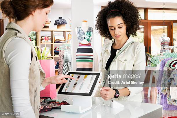 woman shopping in clothing store paying with smart watch - shop till stock-fotos und bilder