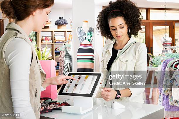 woman shopping in clothing store paying with smart watch - kledingwinkel stockfoto's en -beelden