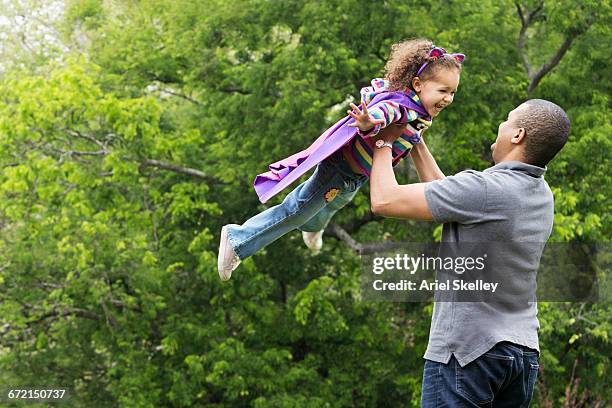 father lifting flying superhero daughter - action hero foto e immagini stock