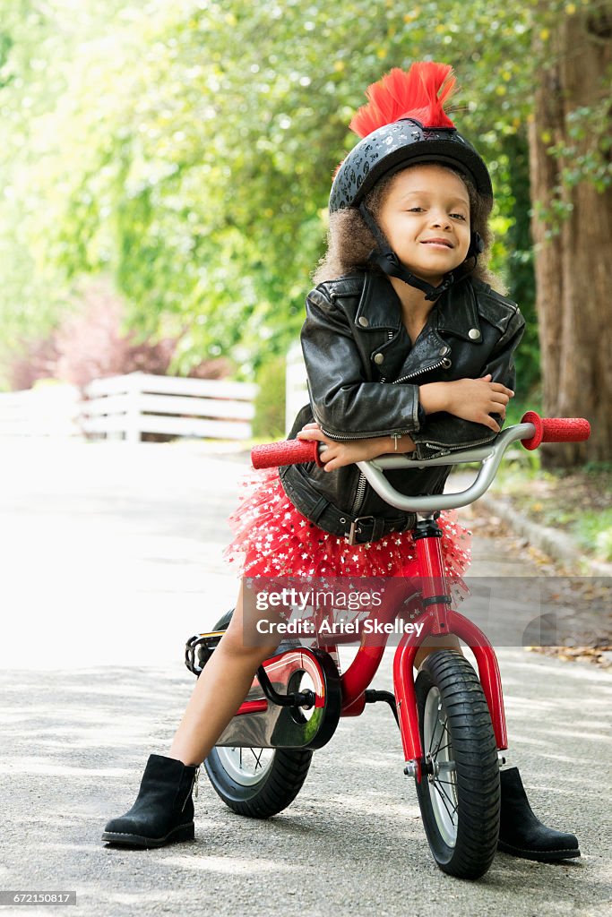 Mixed Race girl posing with attitude in leather jacket on bicycle