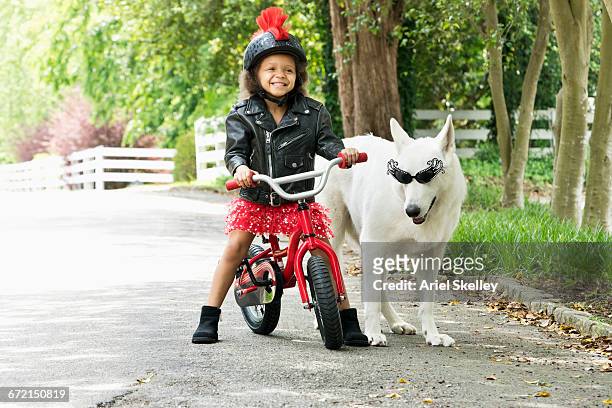 mixed race girl smiling in leather jacket on bicycle with dog - ariel rebel ストックフォトと画像