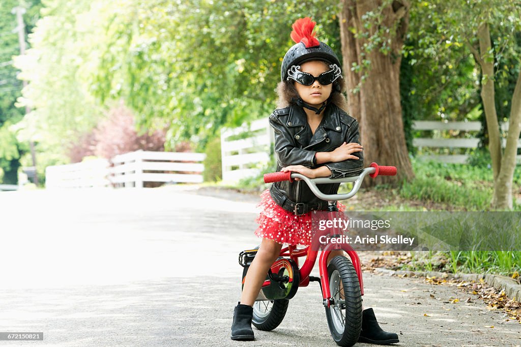 Mixed Race girl posing with attitude in leather jacket on bicycle