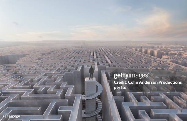 businessman stranded at top of complex maze - complejidad fotografías e imágenes de stock