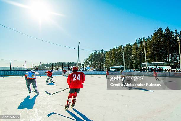 caucasian boys playing ice hockey outdoors - difensore hockey su ghiaccio foto e immagini stock