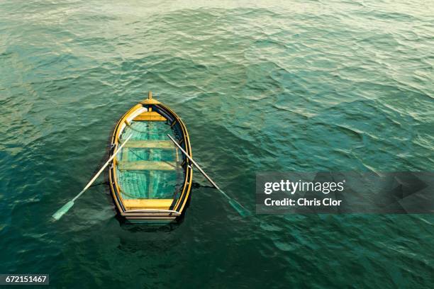 abandoned sinking rowboat in ocean - sinking rowboat stock pictures, royalty-free photos & images