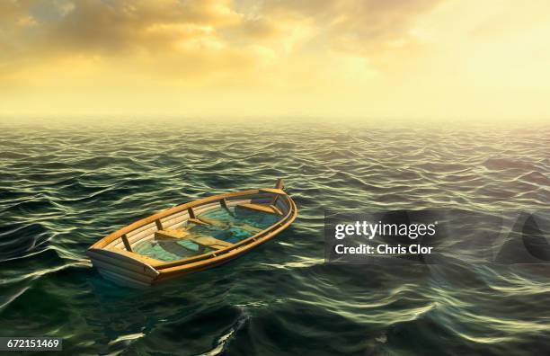 abandoned sinking rowboat in ocean - sinking rowboat stock pictures, royalty-free photos & images