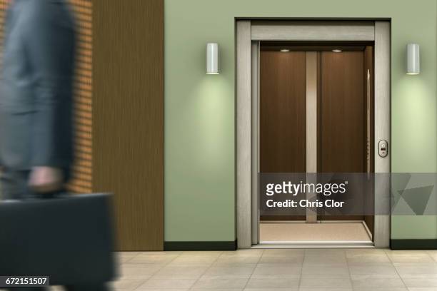 businessman passing open elevator - elevator stock-fotos und bilder
