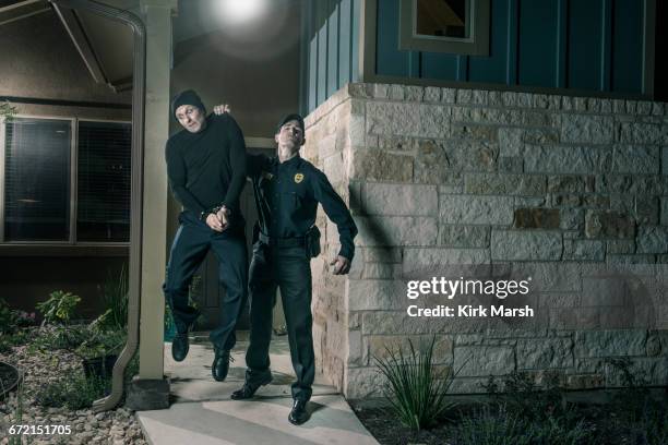 caucasian police lifting burglar in handcuffs - burglar carried stock pictures, royalty-free photos & images