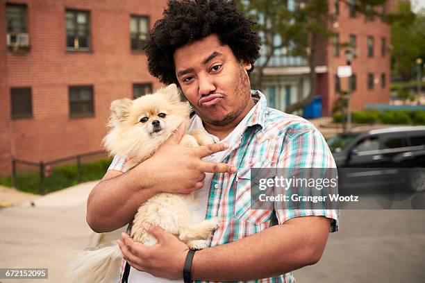 mixed race man gesturing peace with dog in city - geisteshaltung stock-fotos und bilder