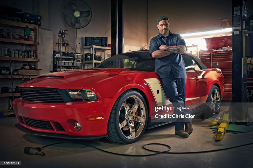 Caucasian mechanic posing on red sports car