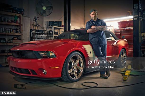 caucasian mechanic posing on red sports car - sportwagen stock-fotos und bilder