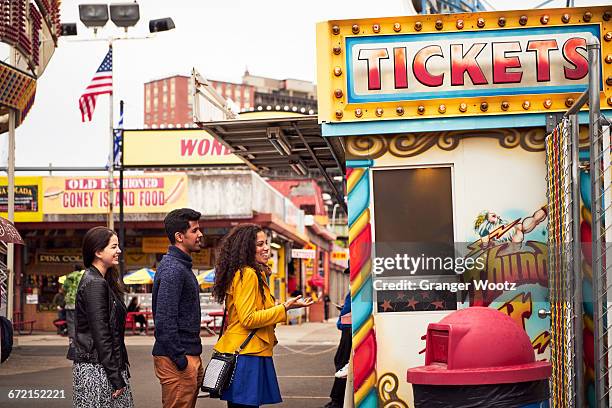 friends waiting in line at amusement park ticket booth - parque de diversiones fotografías e imágenes de stock