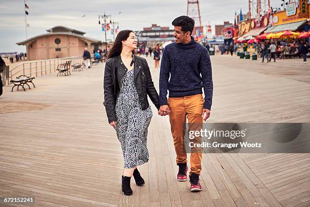 couple walking on boardwalk at amusement park - bulevar fotografías e imágenes de stock