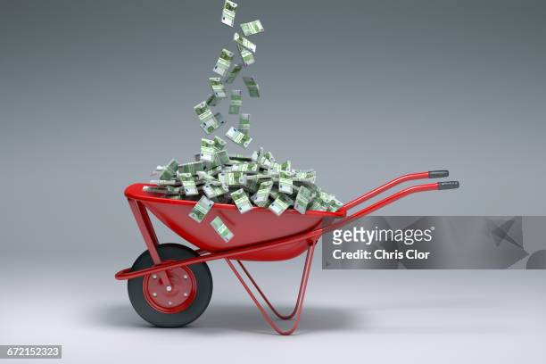 euros falling into red wheelbarrow - money in wheelbarrow stockfoto's en -beelden