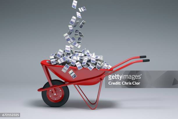 british pounds falling into red wheelbarrow - british pound sterling stock-fotos und bilder