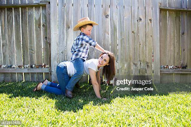 caucasian boy wearing cowboy hat sitting horseback on mother - horses playing stock pictures, royalty-free photos & images