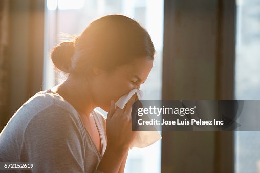 Hispanic woman wiping nose with tissue Hispanic woman wiping nose with tissue