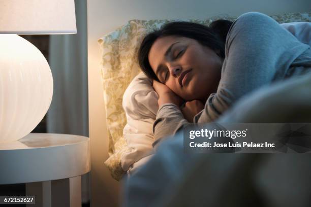 lamp illuminating sleeping hispanic woman - woman sleep bedroom foto e immagini stock