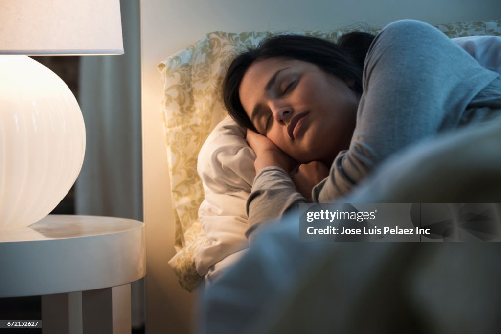 Lamp illuminating sleeping Hispanic woman