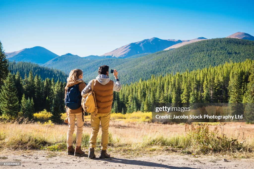 Hispanic couple photographing mountains, Breckenridge, Colorado, United States,