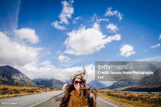 Hispanic woman smiling in road near mountains