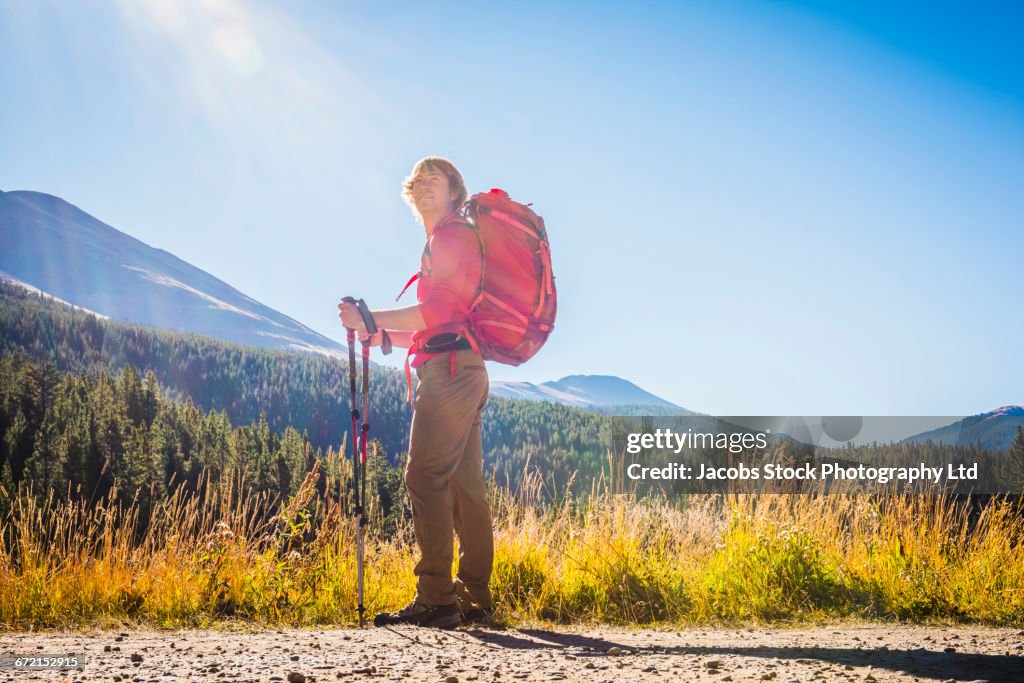 Caucasian hiker with backpack standing near mountains