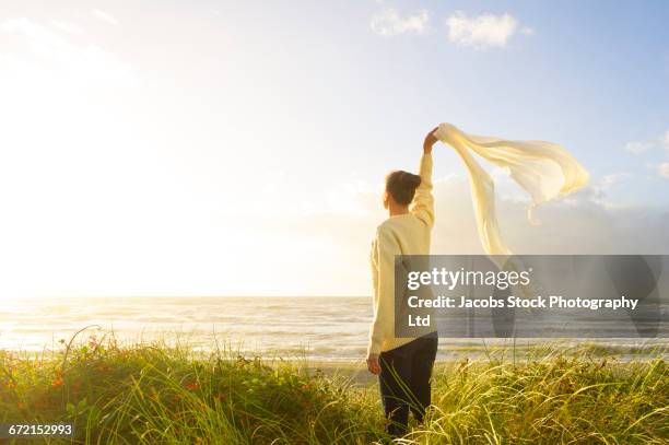 hispanic woman standing in grass at beach waving scarf - scarf isolated stockfoto's en -beelden