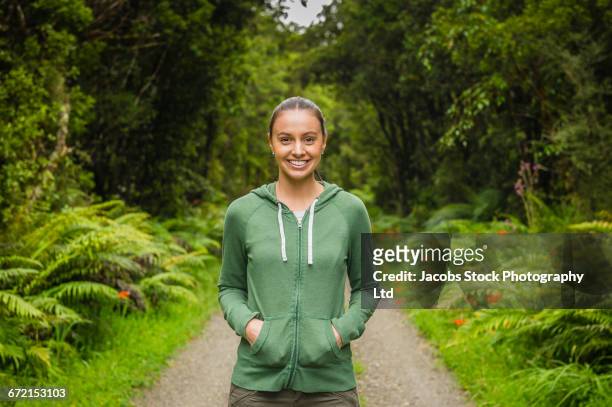 smiling hispanic woman standing on path in lush green forest - forest new zealand stock pictures, royalty-free photos & images