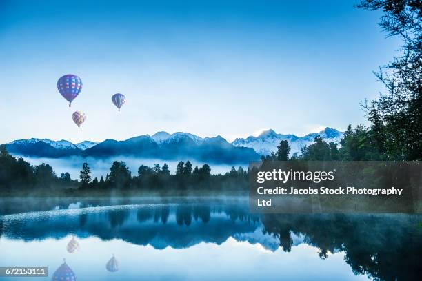 hot air balloons floating over foggy mountain lake - westland stock-fotos und bilder