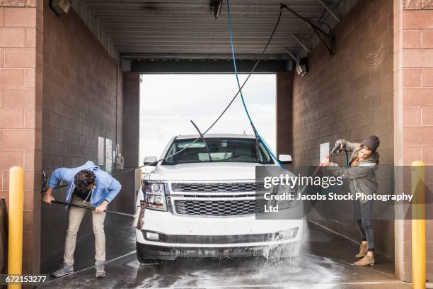 hispanic couple washing car at self-serve car wash - car wash brush fotografías e imágenes de stock