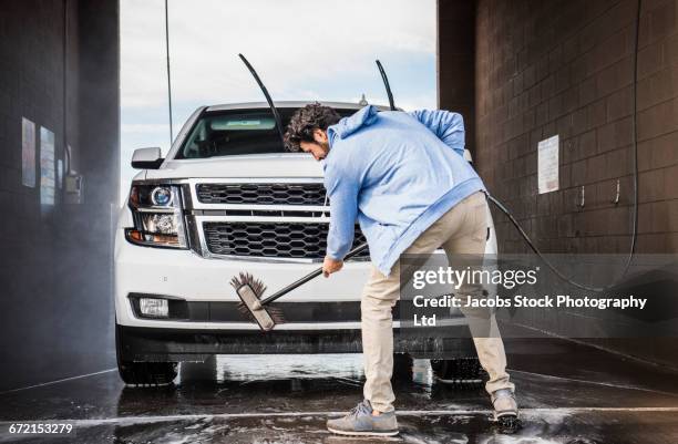 hispanic man brushing car at self-serve car wash - car wash brush fotografías e imágenes de stock