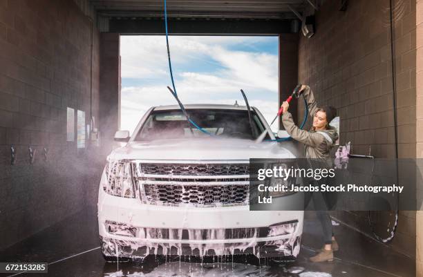 hispanic woman washing car at self-serve car wash - car wash ストックフォトと画像