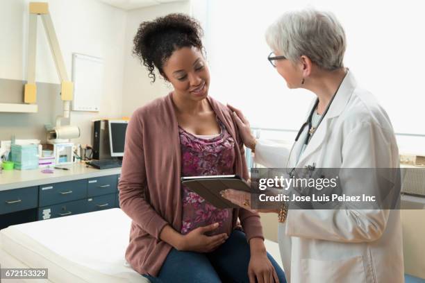 gynecologist with digital tablet comforting pregnant patient - preganant woman stockfoto's en -beelden