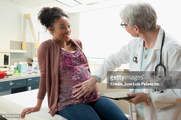 gynecologist with digital tablet feeling belly of pregnant patient - prenatal care stock pictures, royalty-free photos & images