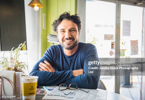 hispanic man with newspaper posing in coffee shop - 35 39 years stock pictures, royalty-free photos & images