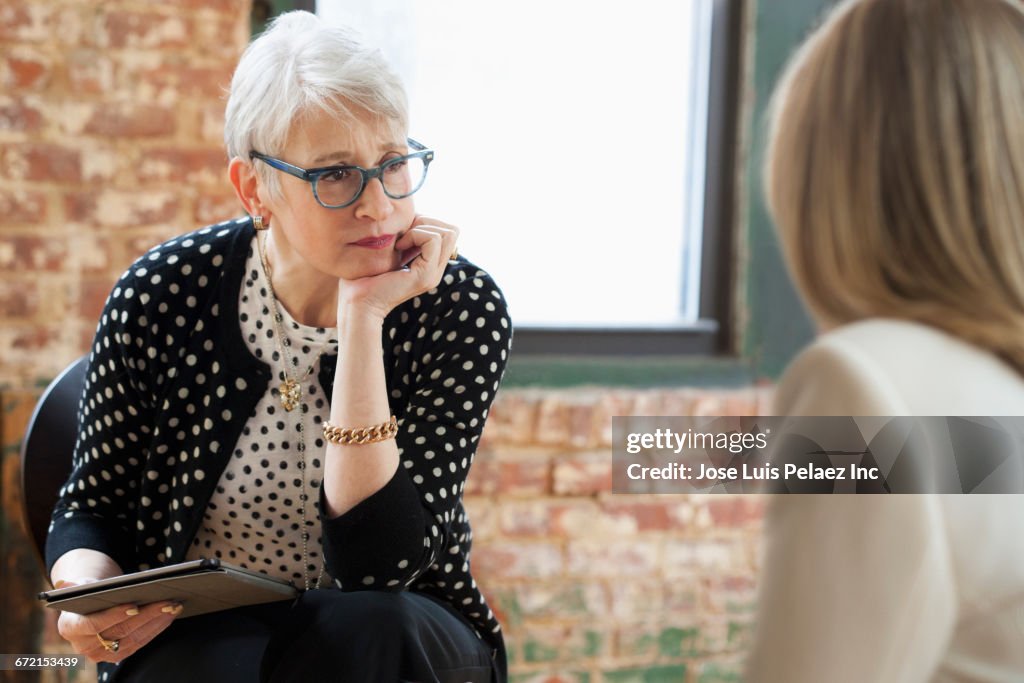 Caucasian businesswomen talking in office with digital tablet