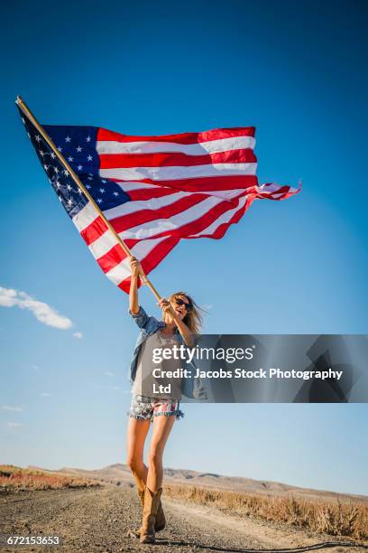 hispanic woman standing in desert waving american flag - holding flag stock pictures, royalty-free photos & images