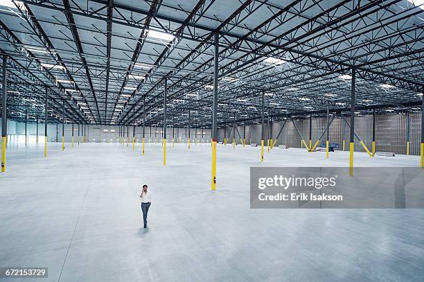 indian businessman talking on cell phone in empty warehouse - new user stockfoto's en -beelden