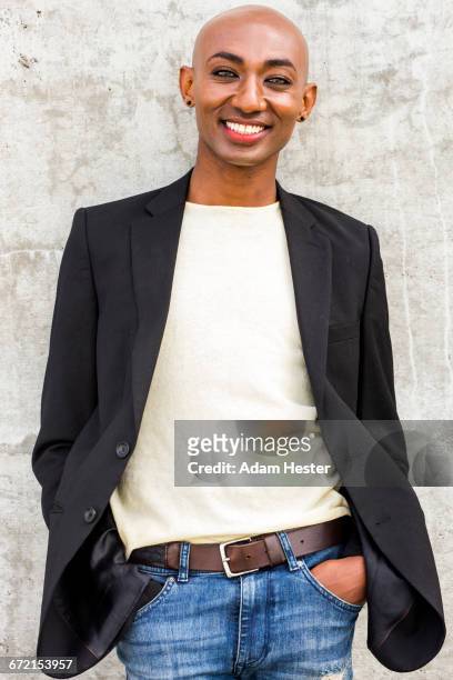 smiling gay black man leaning on concrete wall - androgynous stock pictures, royalty-free photos & images