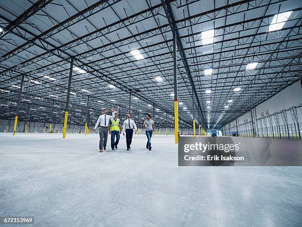 businessmen walking and talking in empty warehouse - architekt mit plan frontal stock-fotos und bilder