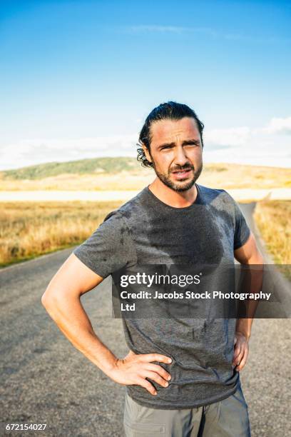 hispanic runner resting in road - schweiß stock-fotos und bilder