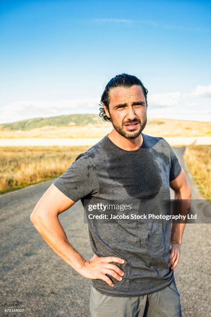 Hispanic runner resting in road