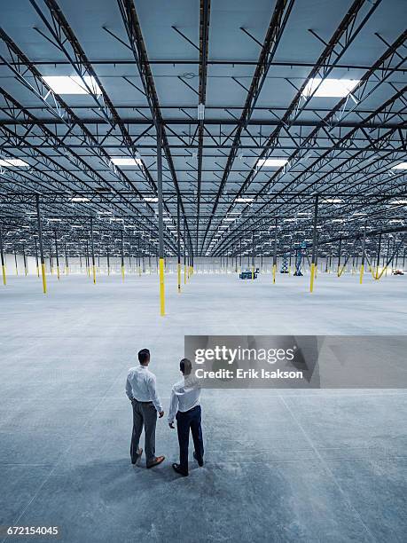 businessmen talking in empty warehouse - new business construction stock pictures, royalty-free photos & images