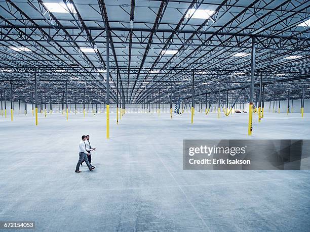 businessmen walking in empty warehouse - business people copy space stock pictures, royalty-free photos & images