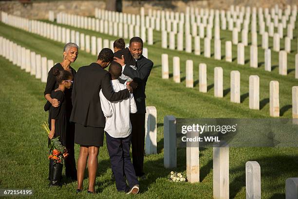 multi-generation black family hugging in military cemetery - luogo di sepoltura foto e immagini stock