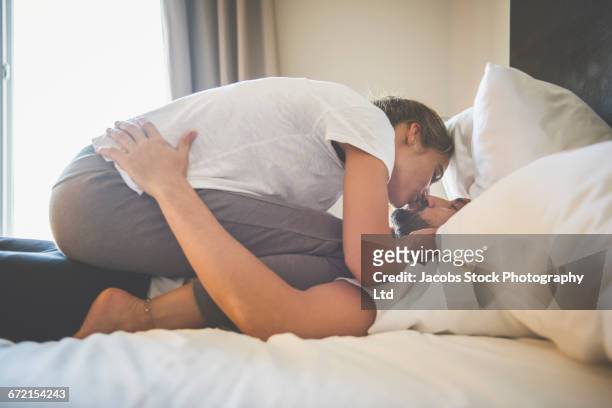 passionate hispanic couple kissing in bed - woman straddling man stock pictures, royalty-free photos & images